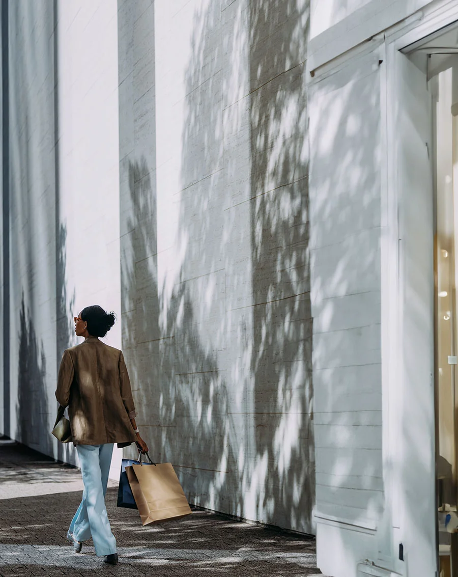 woman with dark hair, holding bags, walking along a sidewalk - Out of town patient resources in New York and New Jersey